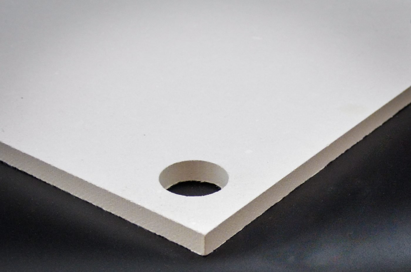 Machined hole and clean cut edge in a white calcium silicate insulation board