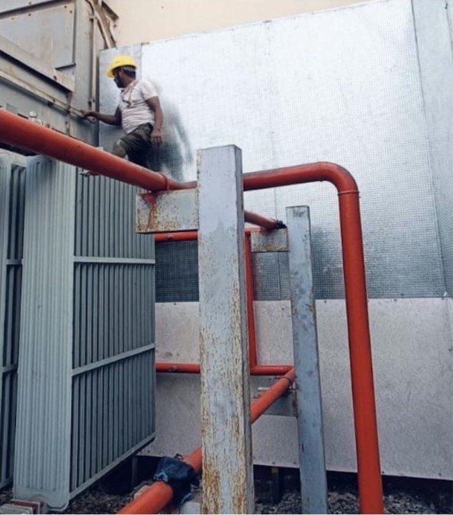 Fitter fixing WedgeSCB steel composite blast wall panels beside an oil-filled transformer