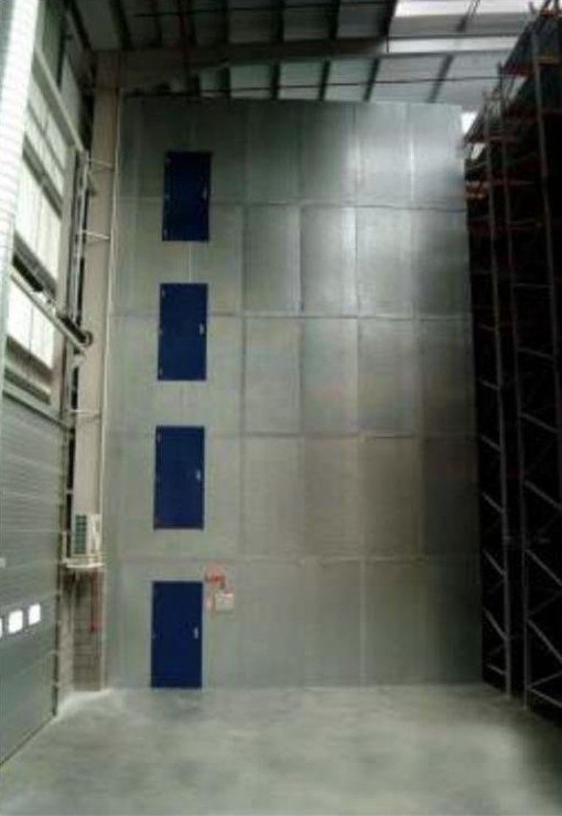 Full-height fire-rated steel composite board wall with fire doors separating an industrial hall